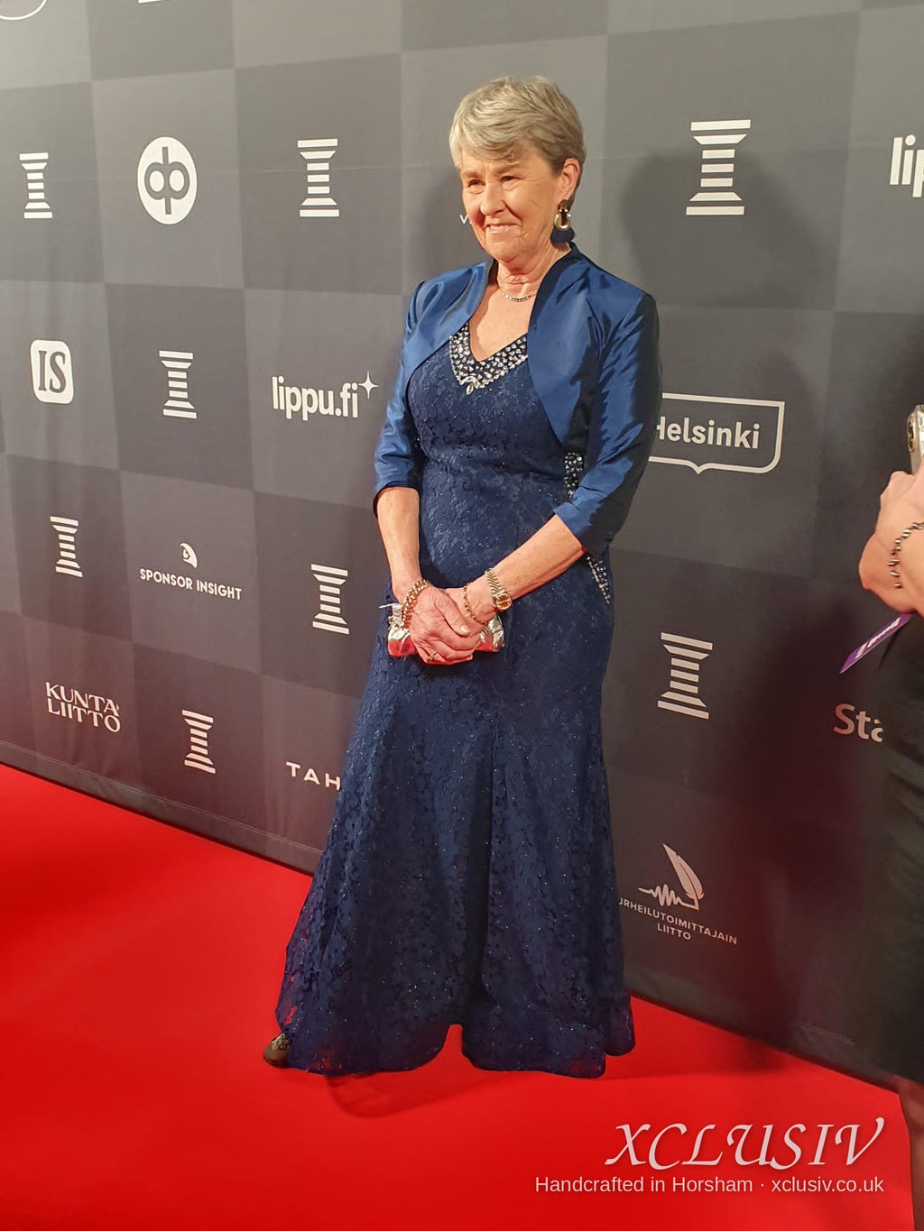 Real XCLUSIV client in her bespoke navy lace gown and bolero on the red carpet