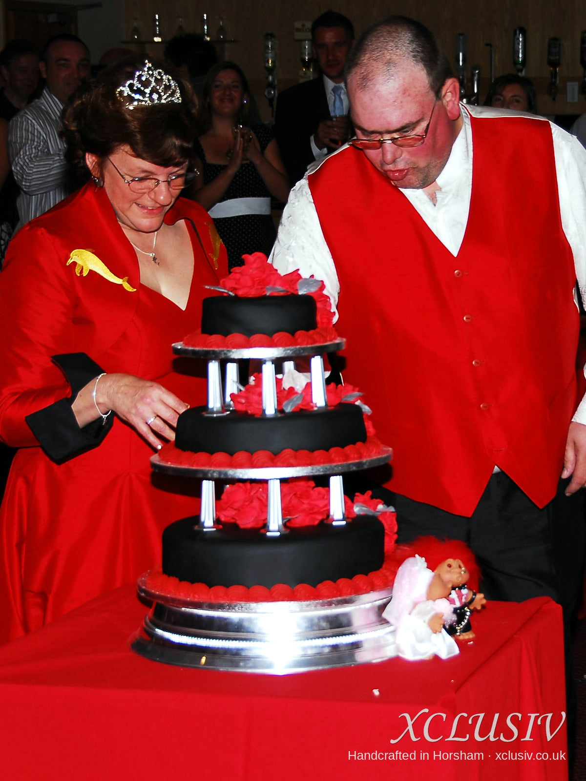 Bride and groom in red and black outfits cutting their red and black wedding cake – XCLUSIV Horsham